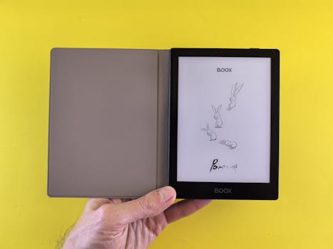 Image of a hand holding an open e-reader with a yellow background.