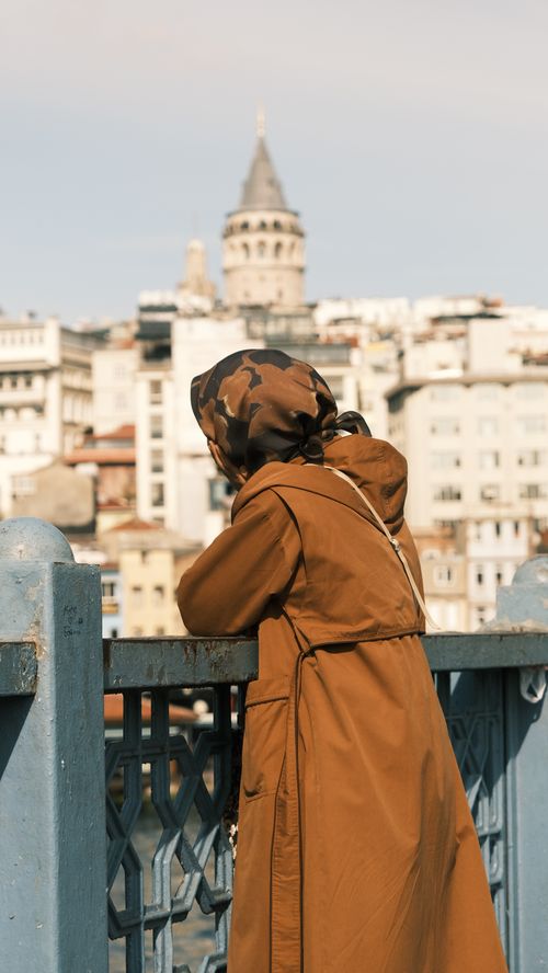 Free Woman in hijab views Istanbul's Galata Tower from the bridge. Stock Photo