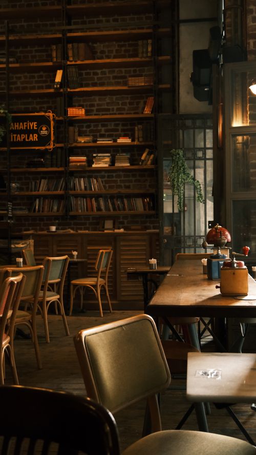 Free Warm vintage library cafe with wooden shelves, books, and rustic decor, perfect for cozy reading and relaxation. Stock Photo