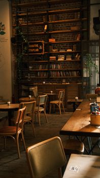 Warm and inviting vintage cafe featuring wooden tables, chairs, and bookshelves.