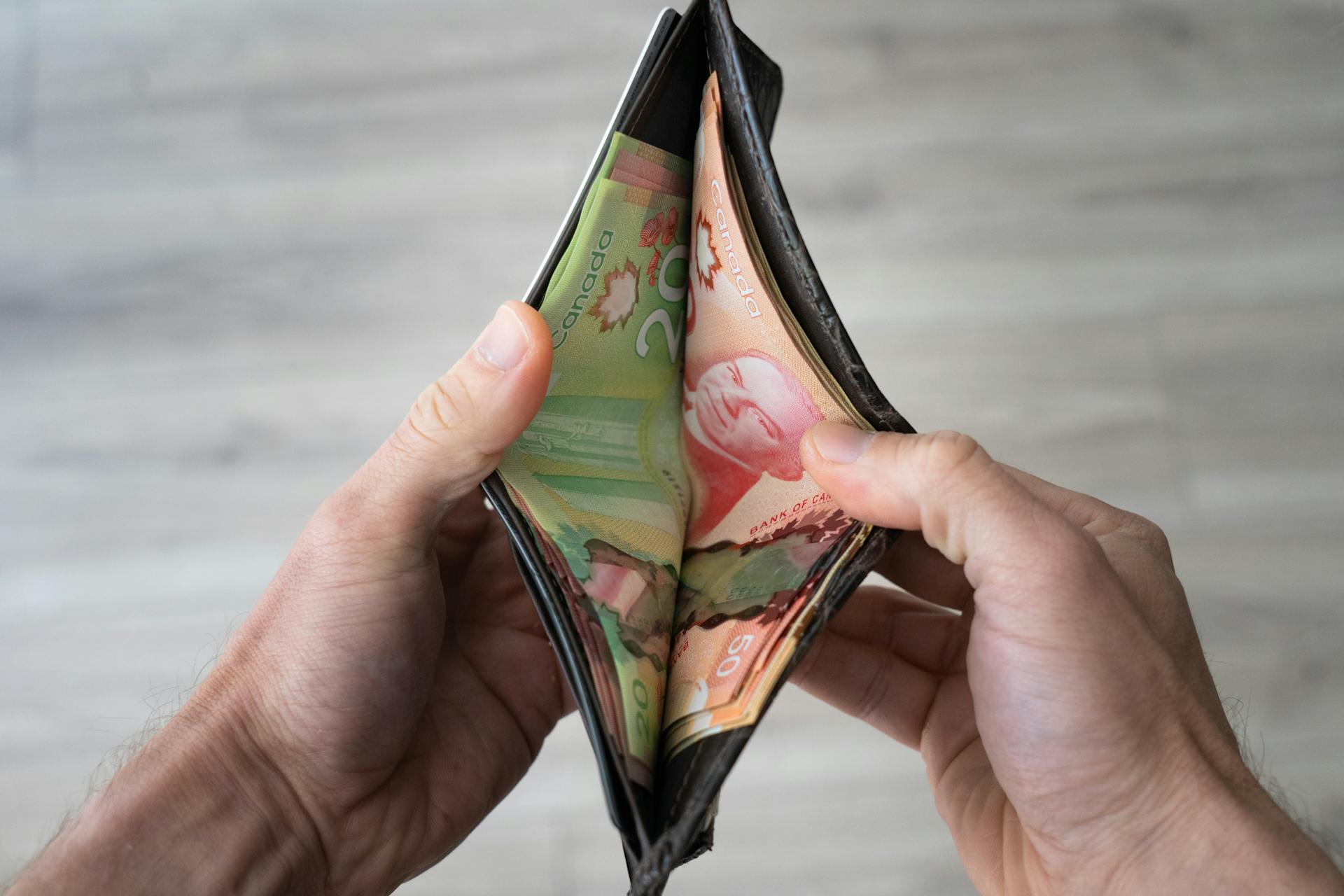 Image of hands holding an open wallet with Canadian banknotes visible, representing personal finance.