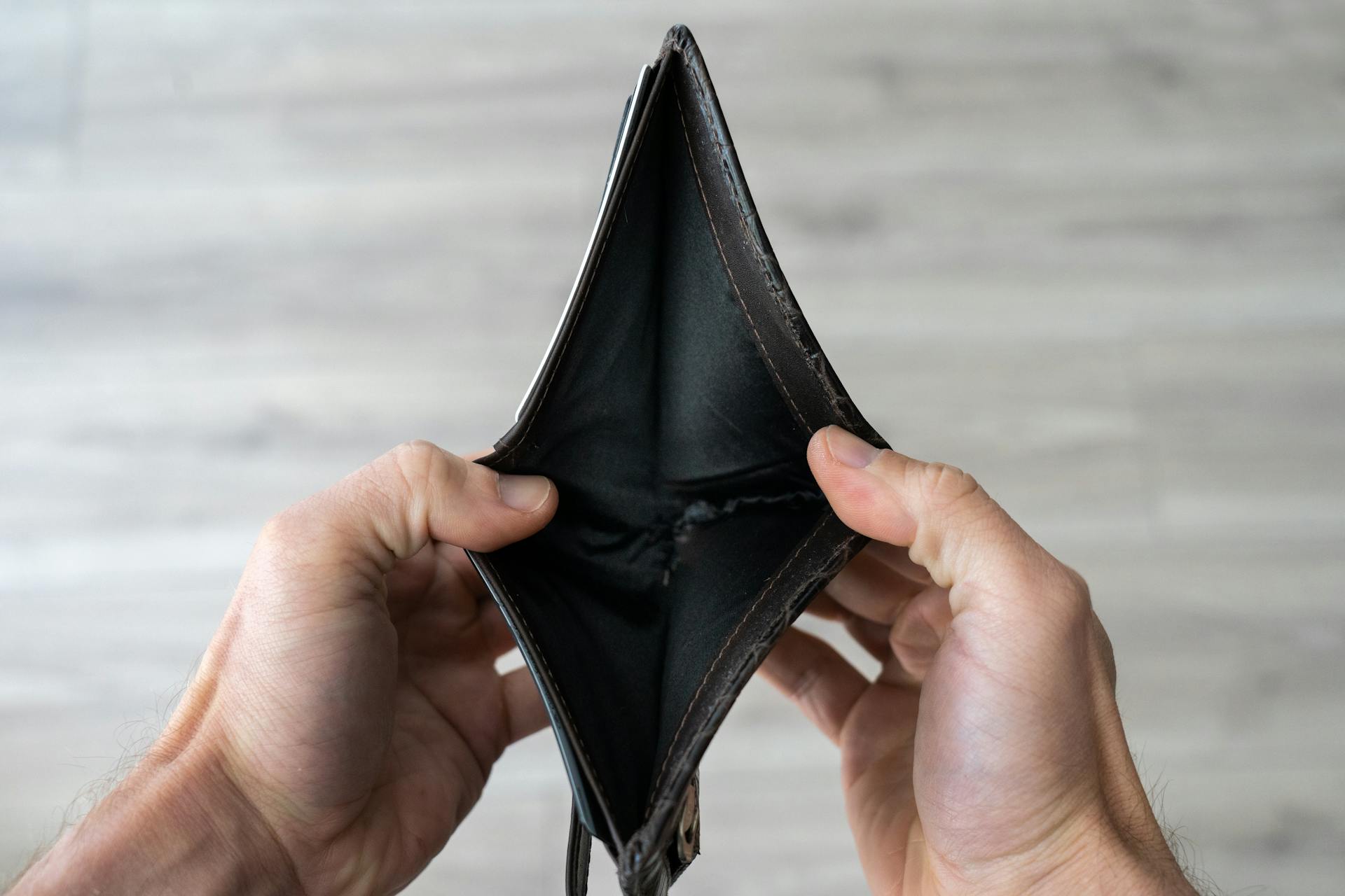 Close-up of hands holding an empty wallet, symbolizing financial difficulties and lack of funds.