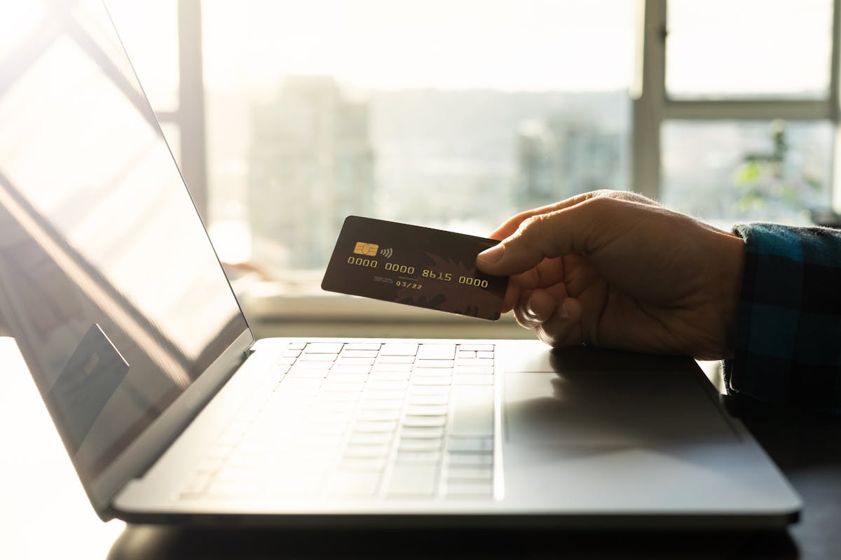 Primo piano di una carta di credito davanti a un laptop per acquisti online