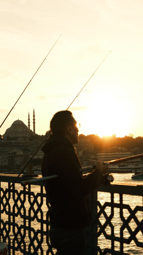 Free Silhouette of a man fishing at sunrise on Istanbul's iconic Galata Bridge. Stock Photo