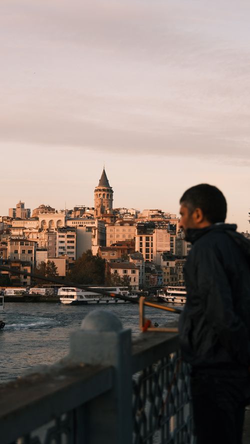 Free A serene view of a cityscape with Galata Tower from a riverside balcony during sunset. Stock Photo