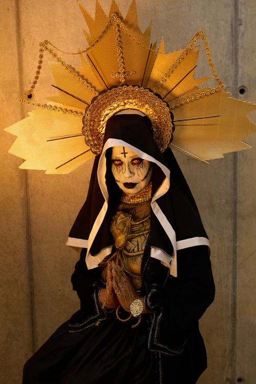 Free A striking portrait of a person in Gothic attire, featuring a golden halo and dramatic makeup. Stock Photo