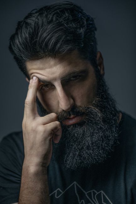 A moody portrait of a bearded man deep in thought, captured in low light. A moody portrait of a bearded man deep in thought, captured in low light.