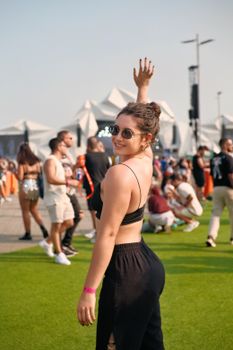 Woman in sunglasses celebrates at an outdoor music festival, exuding joy and energy.