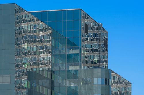 Free Reflective glass building facade in Amsterdam, capturing modern architecture against a clear blue sky. Stock Photo