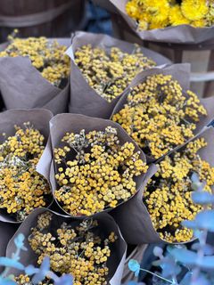 Dried yellow flower posies wrapped in kraft paper — photo by Natalia S on Pexels
