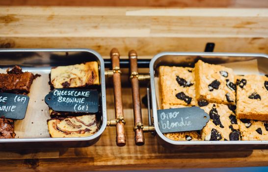 A tempting display of gluten-free brownies and blondies in trays, perfect for dessert lovers.