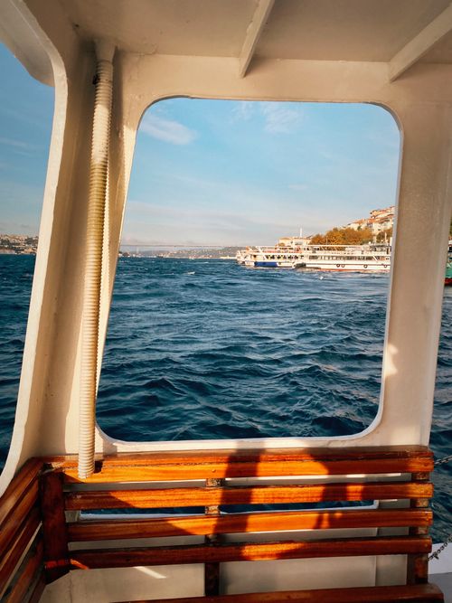 Free View of a bustling waterway from a boat's interior, capturing city skyline and ocean. Stock Photo