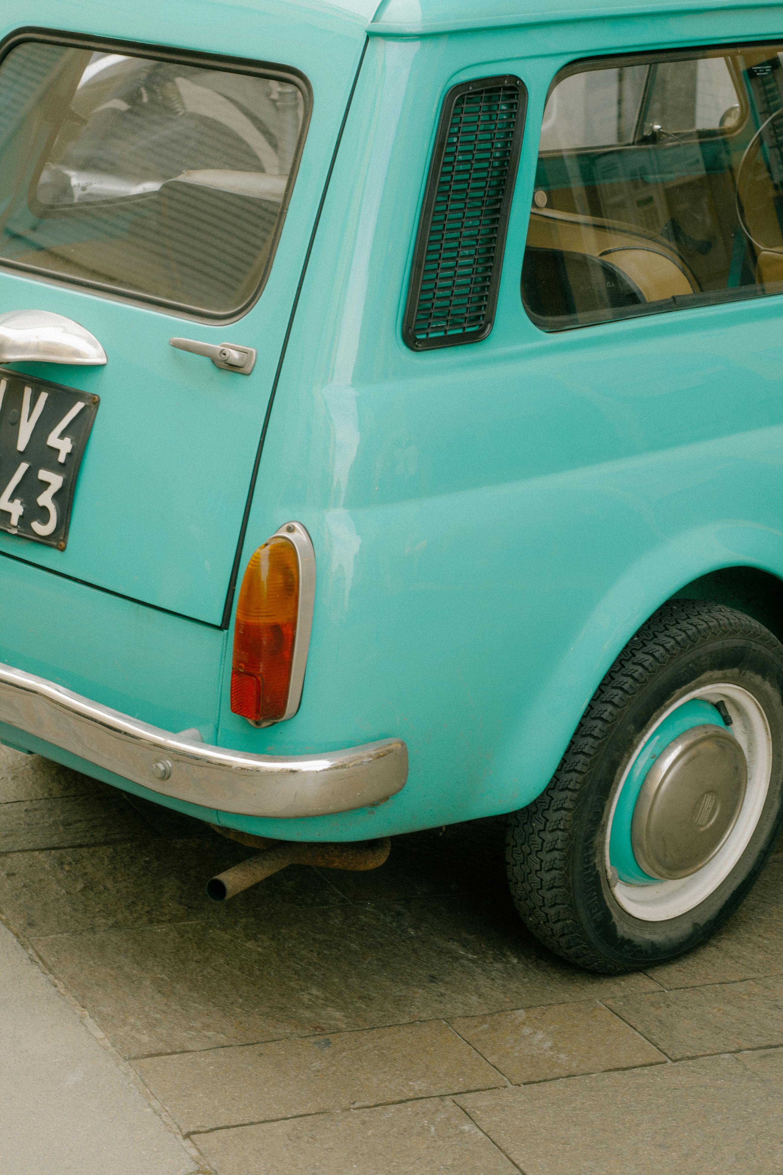 Close-up of a classic turquoise car parked on a city street, showcasing retro style.