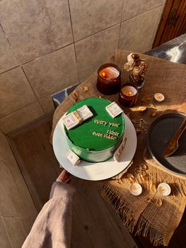 Green cake with cash decorations and candles, perfect for celebrations.