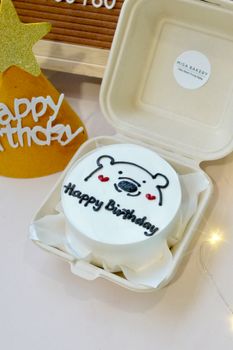 Adorable bear-themed birthday cake in eco-friendly packaging with festive decor.