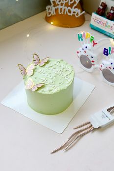 A beautifully decorated pastel green birthday cake with paper butterflies and birthday decorations.
