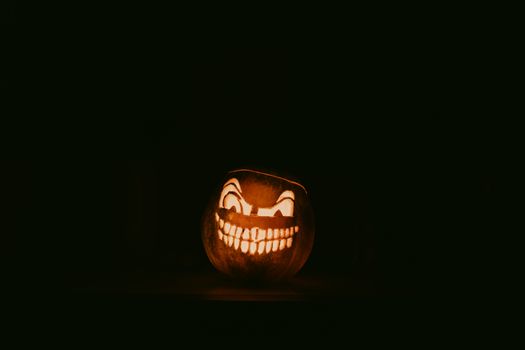 Eerie jack-o'-lantern with sinister smile glowing in the dark, perfect for Halloween.