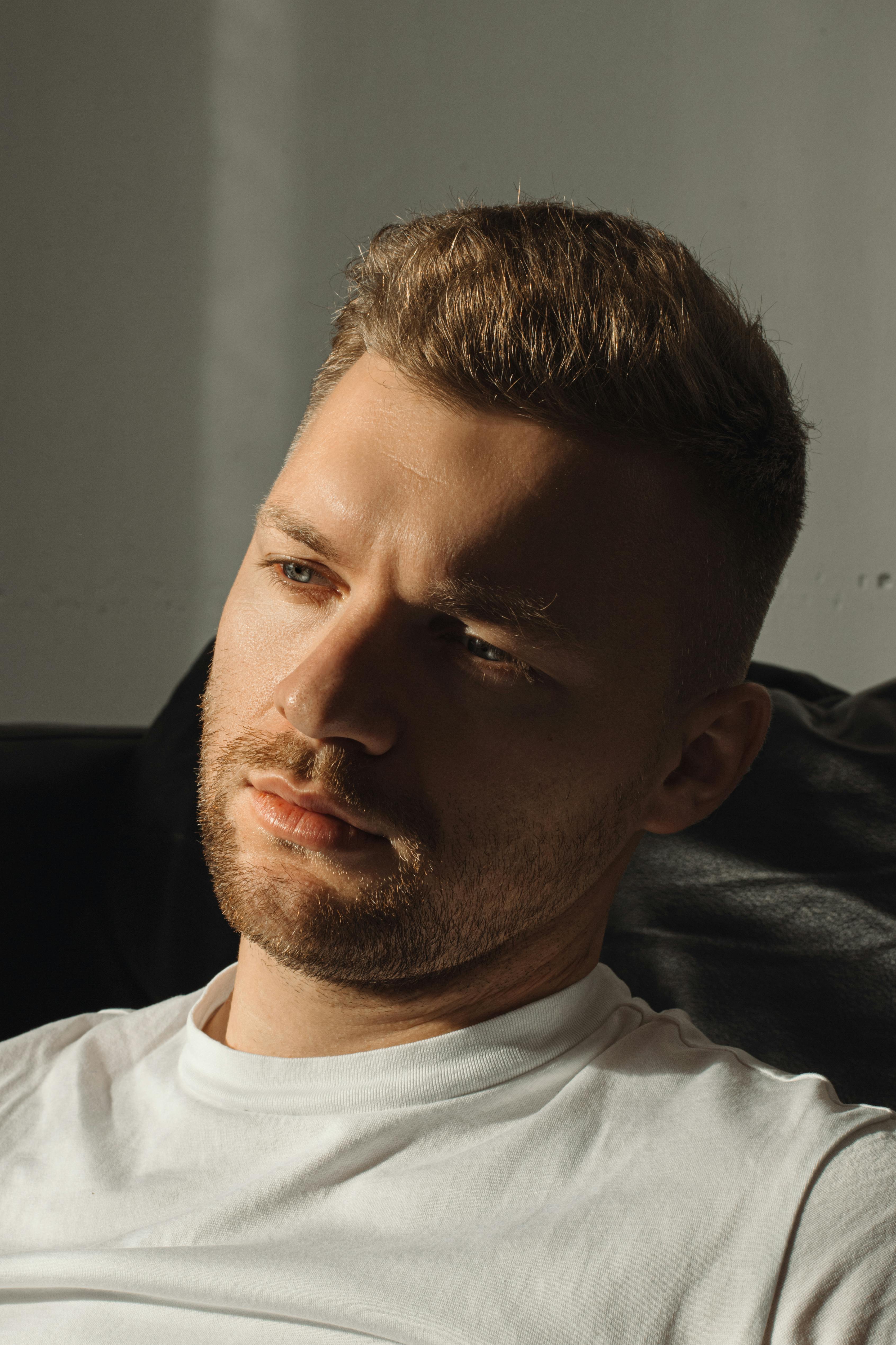 Pensive young man in natural light — thoughtful human unposed portrait signalling authenticity