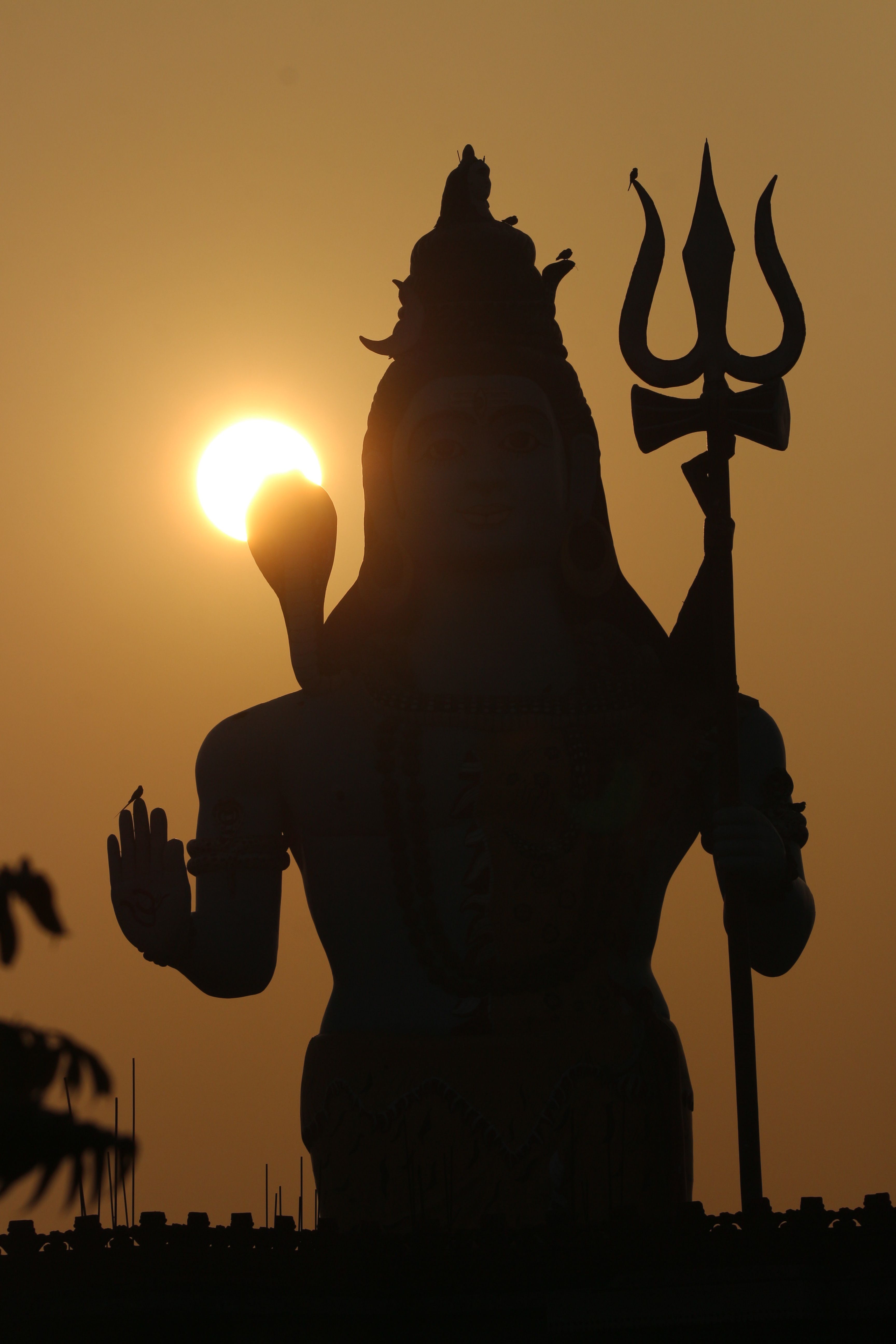Silhouette of Hindu deity Shiva with trident during a stunning sunset.