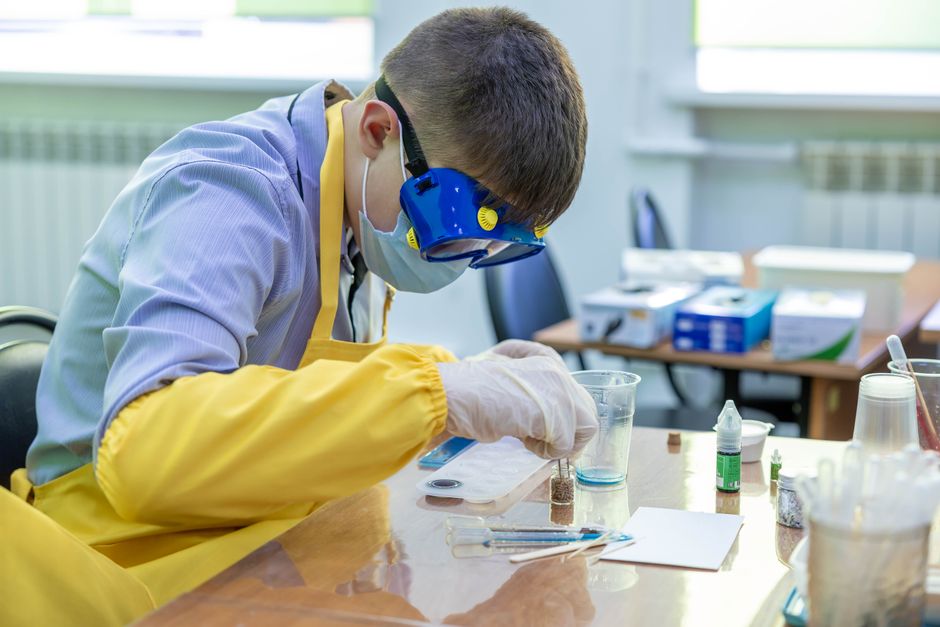 Student in protective gear performing an experiment at a top university in USA for chemical engineering