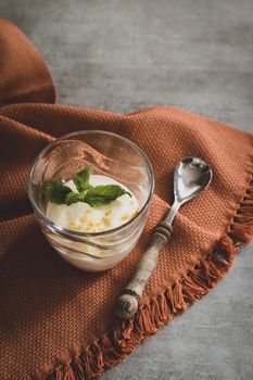 Delicious dessert with mint leaves in a glass, atop a textured tablecloth, creating a refreshing and elegant scene.