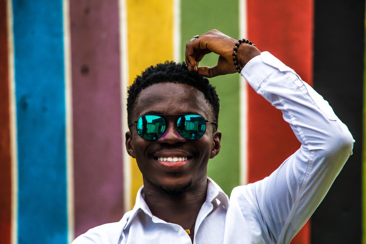 happy man wearing sunglasses smiling in front of a vibrant striped wal