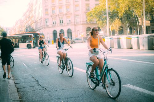 Free Three women cycle through a sunny city street, embracing urban life and leisure. Stock Photo