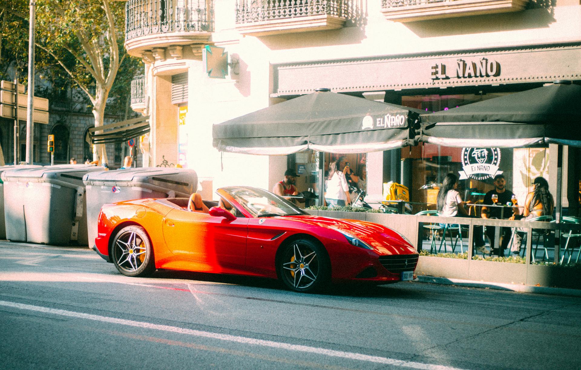 A vibrant red convertible sports car parked outside El Naño cafe in an urban setting.