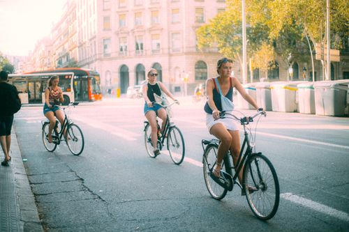 Free Three women casually biking on a sunny urban street, capturing a relaxed lifestyle scene. Stock Photo