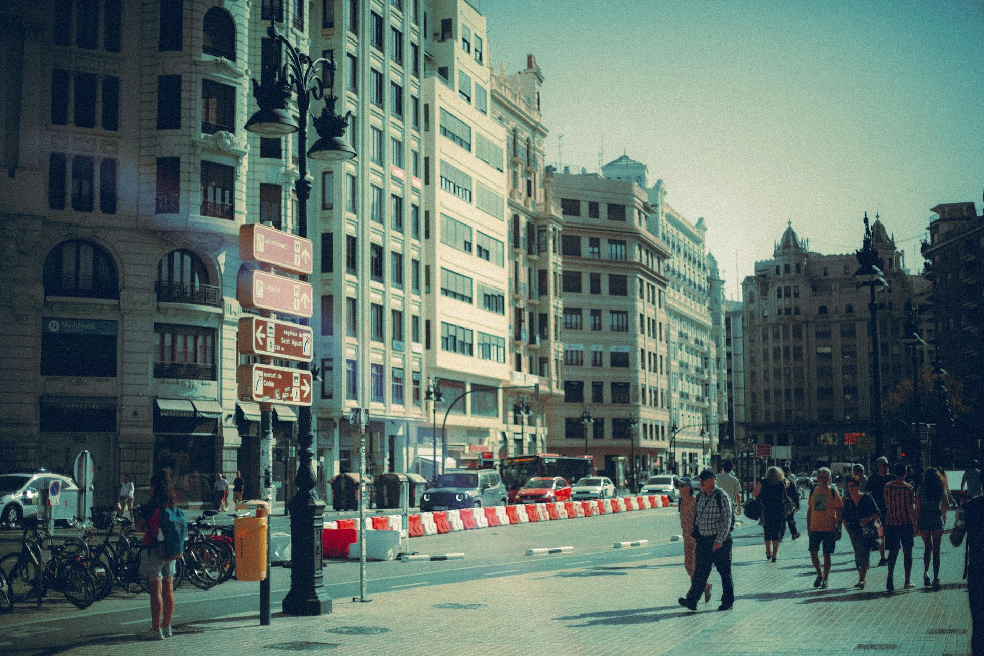 Vibrant city street scene with historical architecture and pedestrians walking on a sunny day.