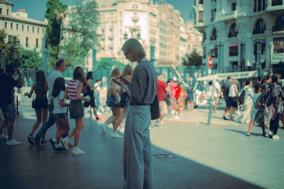 Una mujer usa su teléfono inteligente en una bulliciosa plaza de una ciudad europea.