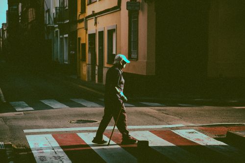 Free Street view of a person crossing a quiet intersection in the city. Stock Photo