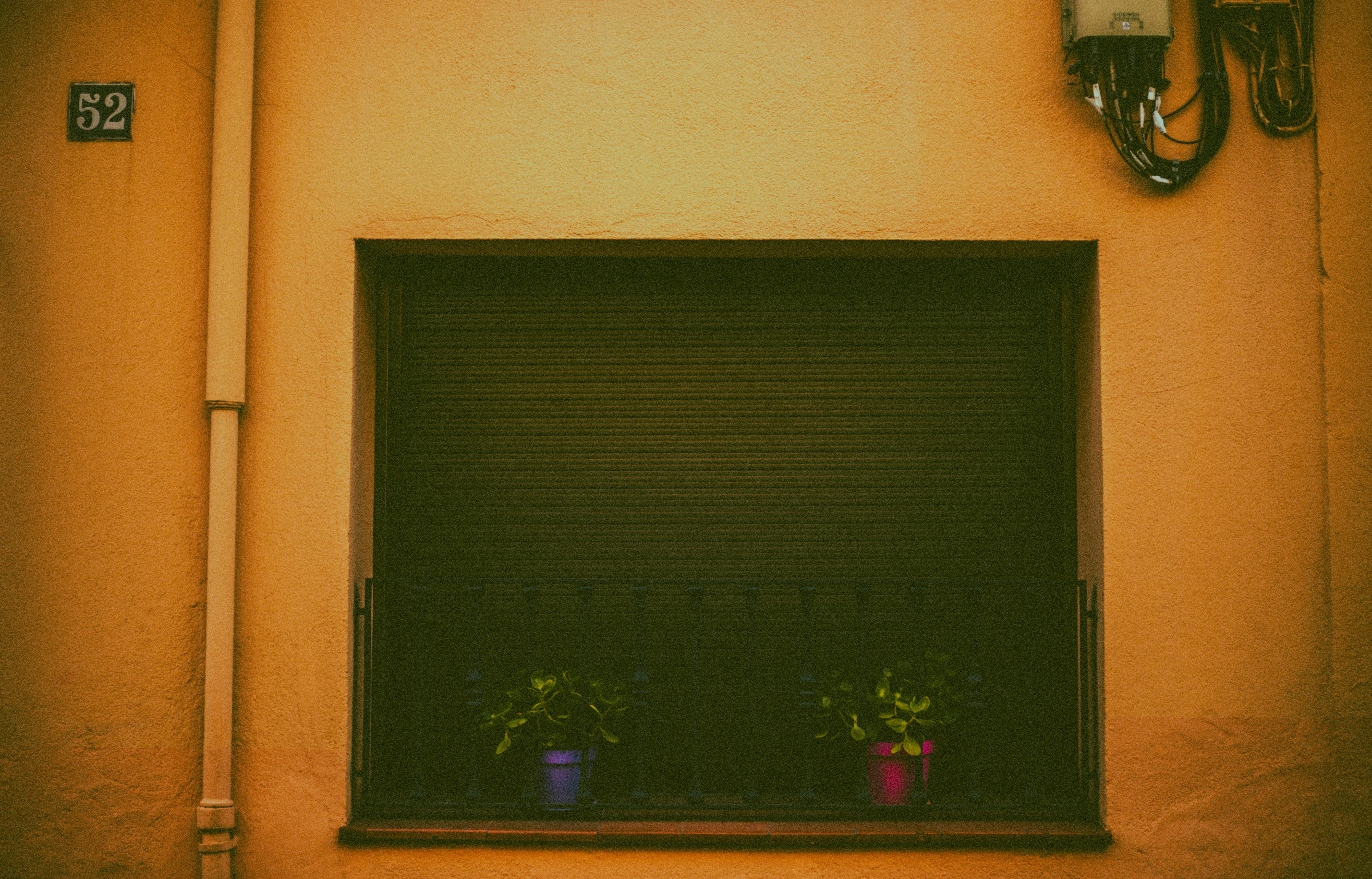 Gratuit O fereastră rustică cu jaluzele închise și două ghivece colorate pe un balcon de fier. Fotografie de stoc