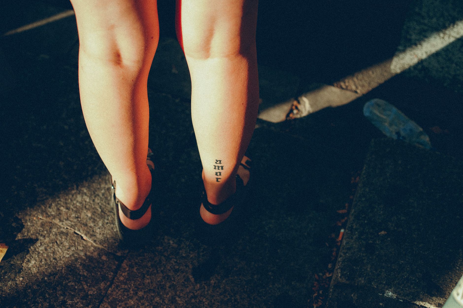 Kleines Wadenmotiv-Tattoo bei einer Frau im Sonnenlicht