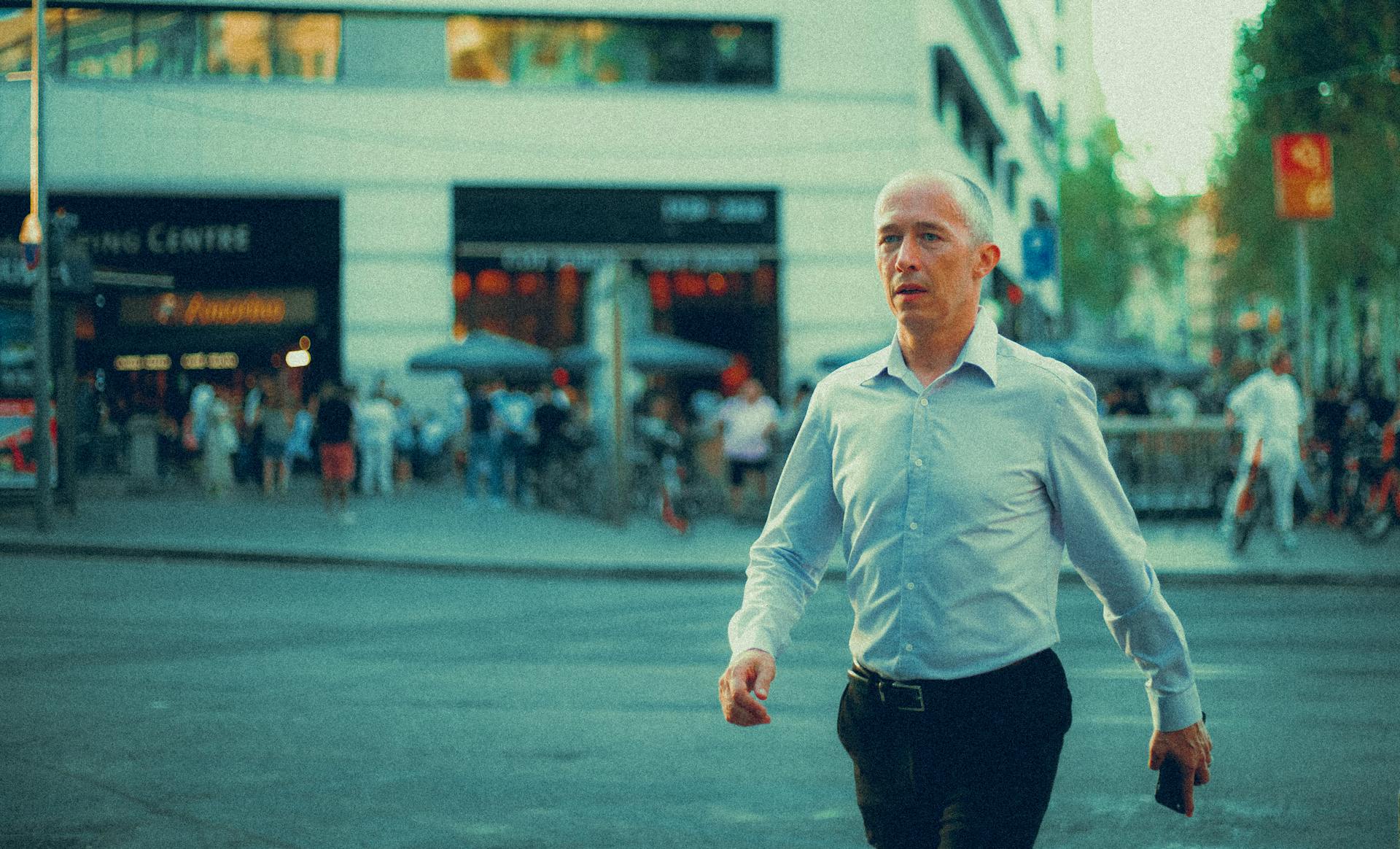 Confident businessman walking through a busy city street in daylight.