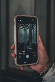 Close-up of hand holding smartphone capturing an ornate room interior.