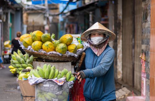 Free Woman selling papayas and bananas on a bustling street in Ho Chi Minh City, Vietnam. Stock Photo