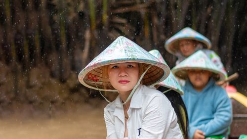 Free A scene of people wearing traditional hats during a rainy boat ride in Mỹ Tho, Vietnam. Stock Photo