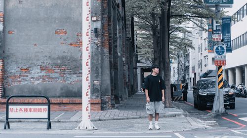 Free Person standing by weathered brick wall on urban street corner. Stock Photo