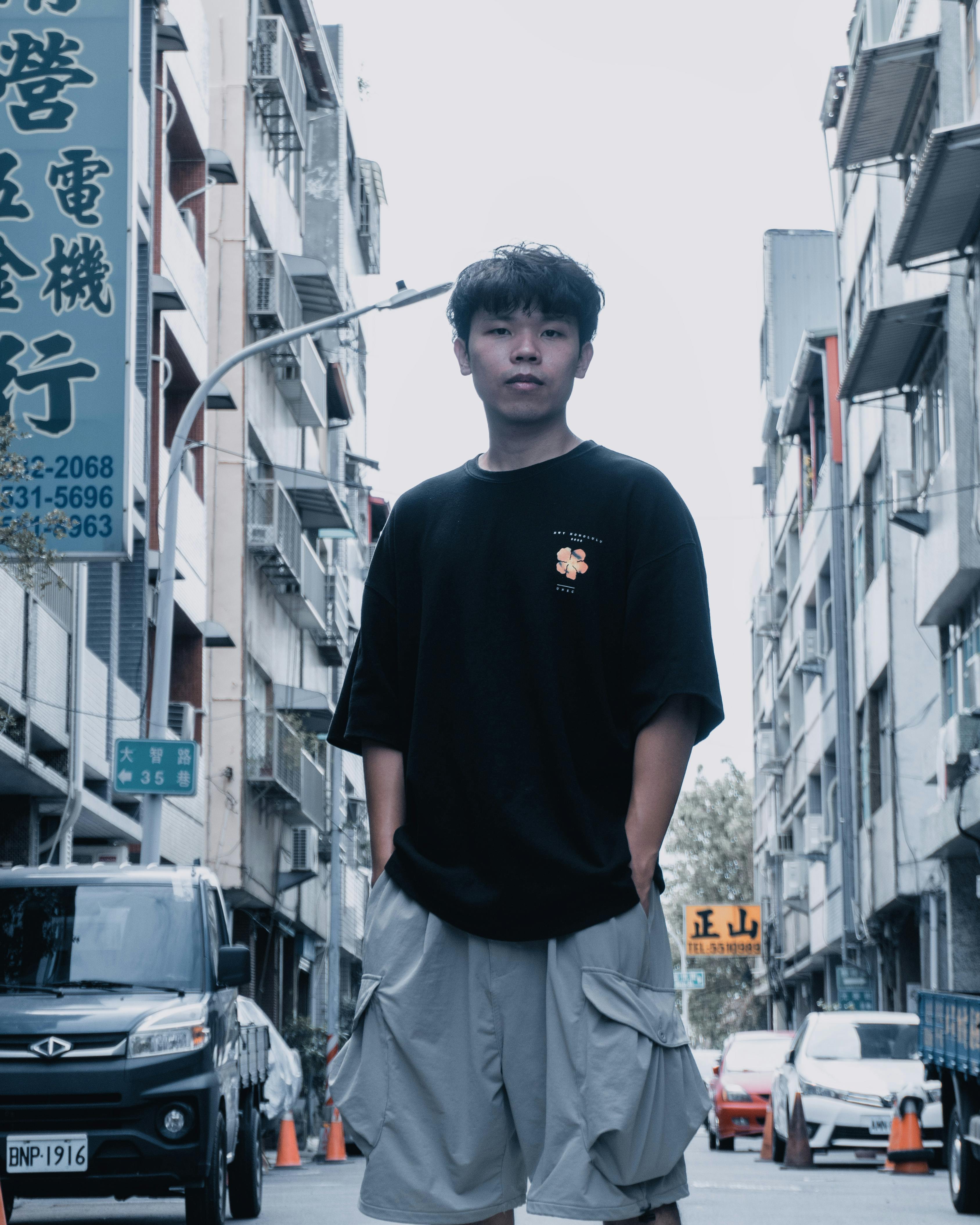 Young man poses confidently in bustling city street setting.