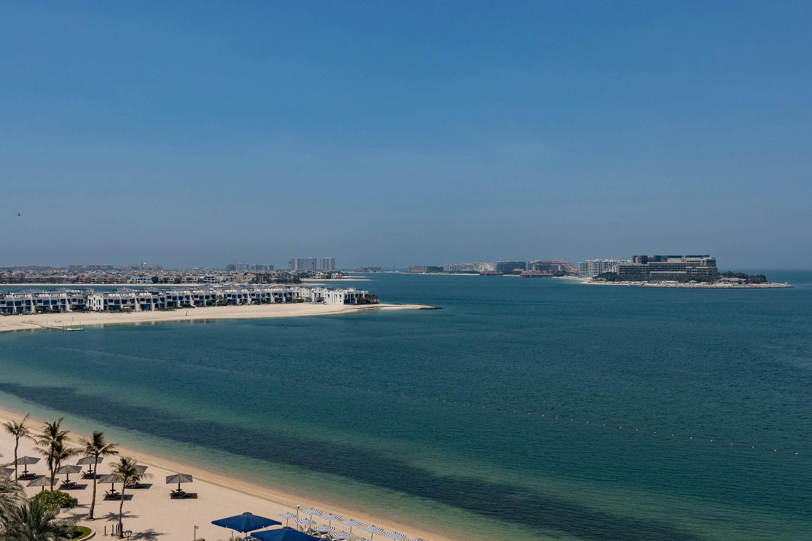 Scenic aerial view of the Palm Jumeirah coastline in Dubai, UAE, featuring luxury villas and clear blue waters.