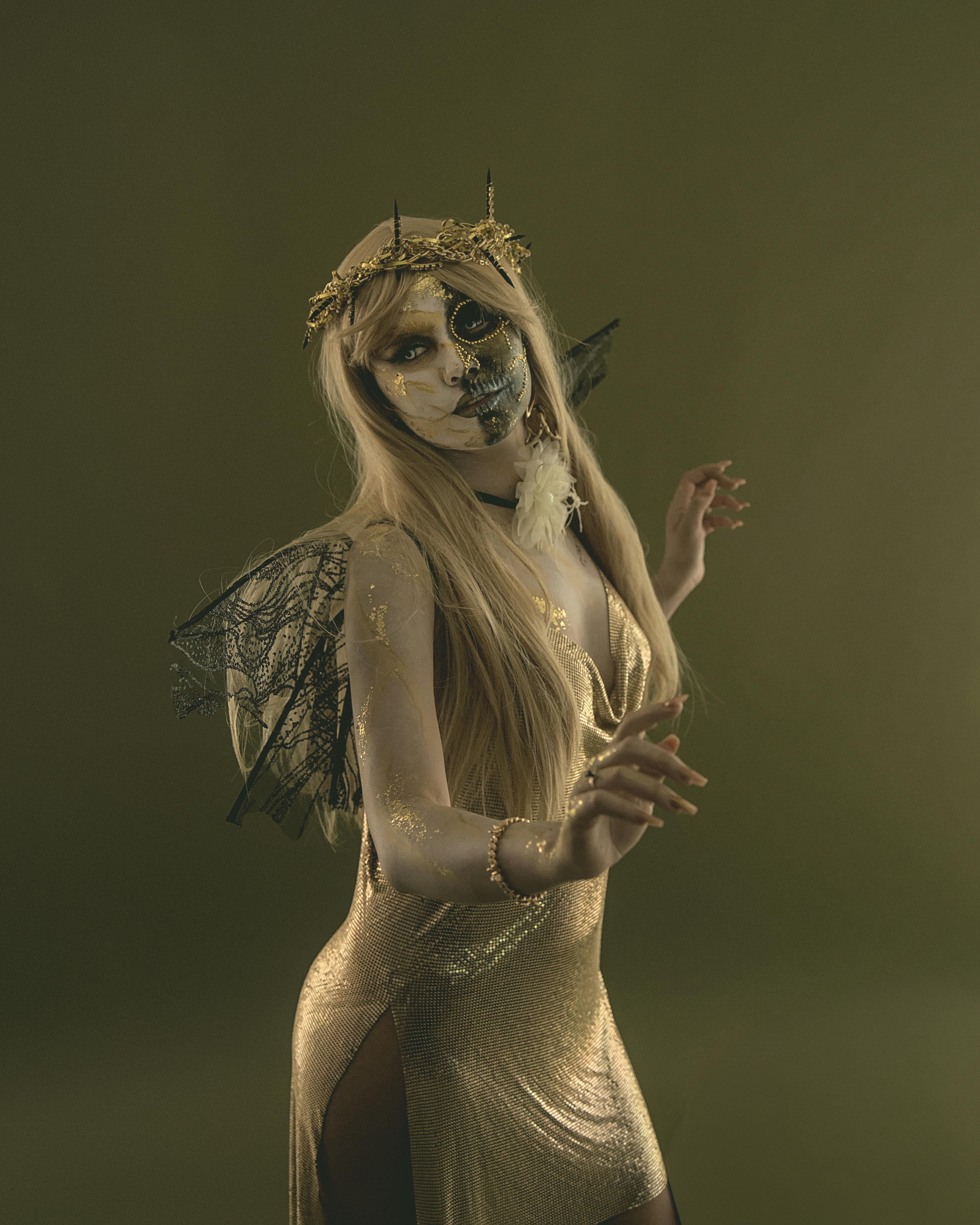 Enchanting woman in costume with face paint and wings, capturing Halloween spirit.