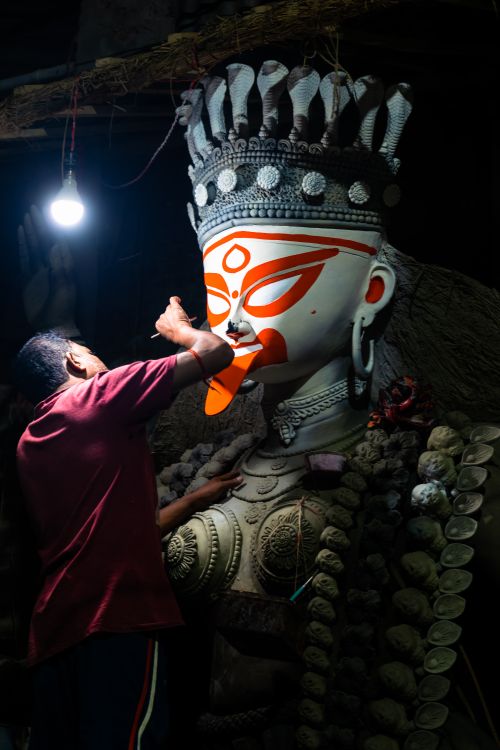 Free An artist carefully details a Goddess Kali idol in a Kolkata workshop, capturing cultural artistry. Stock Photo