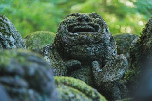 Free Mystical moss-covered stone statue with a lush, green forest backdrop, conveying tranquility and calm. Stock Photo