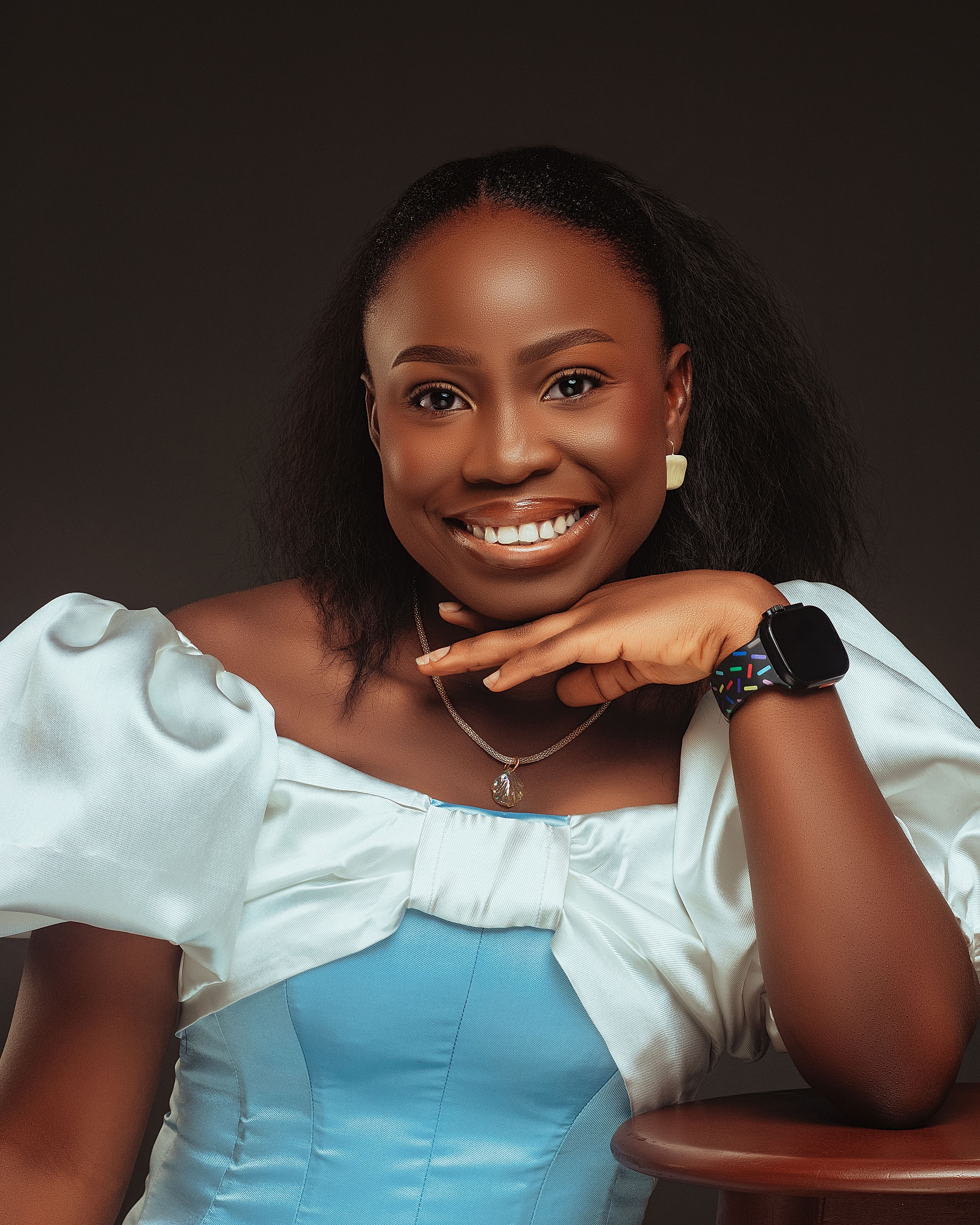 Portrait of a cheerful African woman in a stylish dress with jewelry indoors.