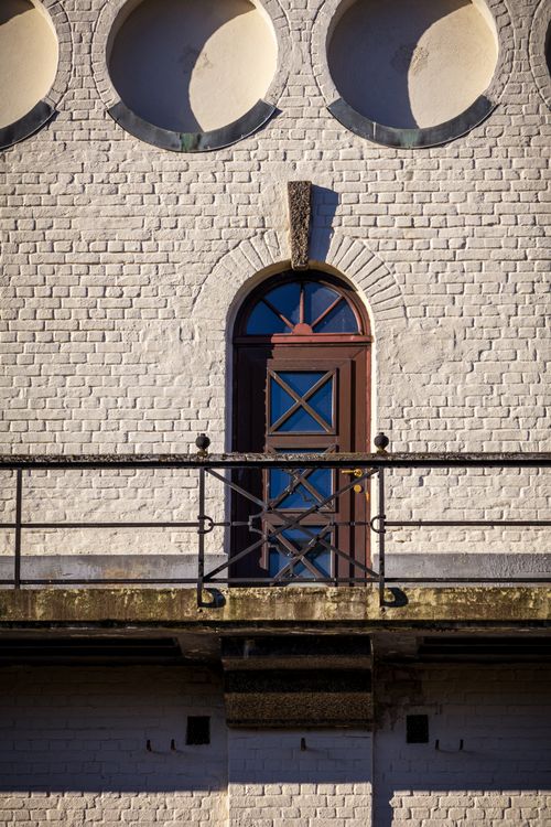 Free Close-up of a vintage arched doorway on a brick wall with balcony railings. Stock Photo