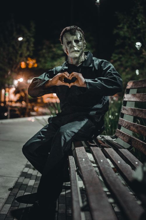 Free Person in horror costume sitting on bench at night, creating a Halloween vibe. Stock Photo