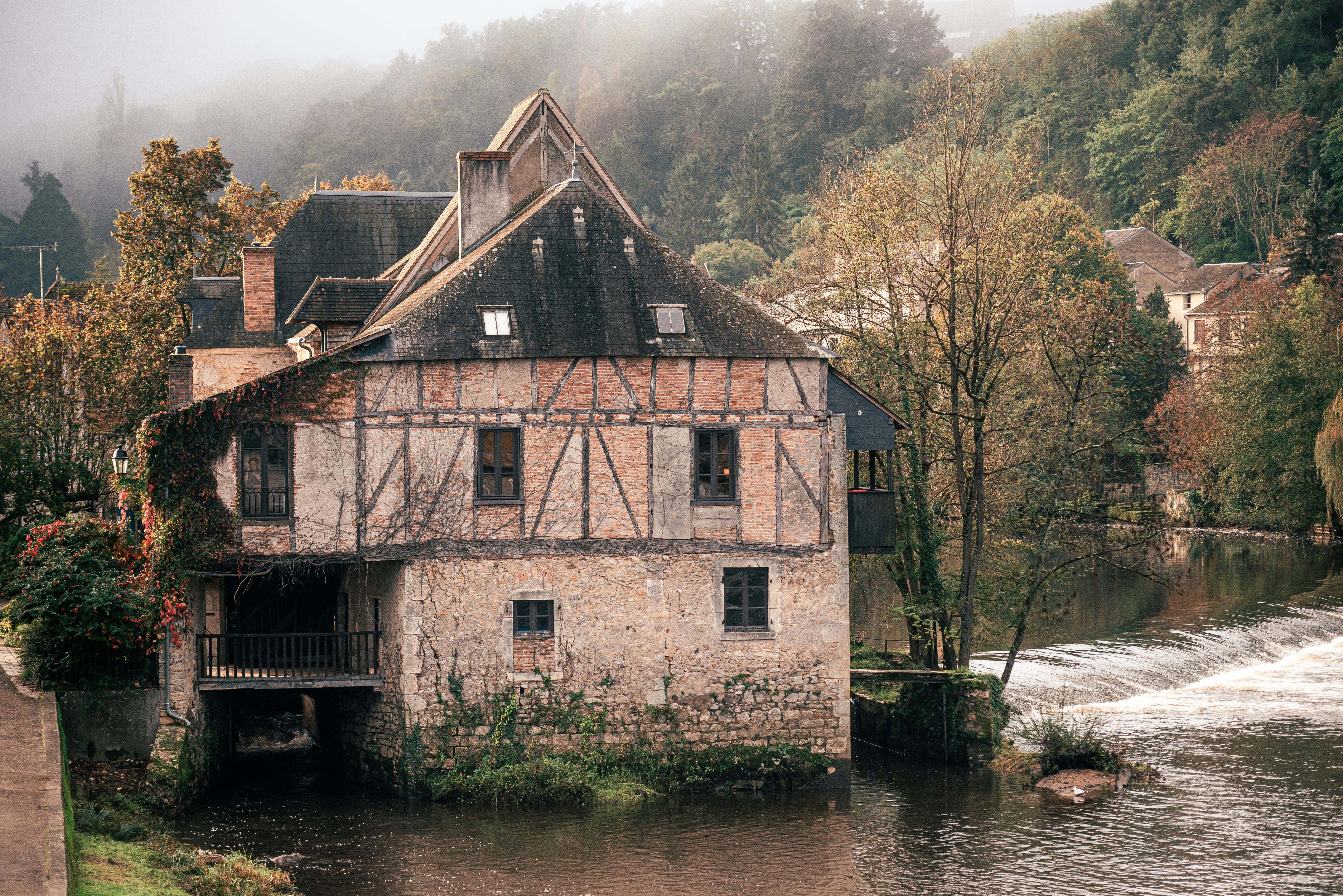 Un chalet rustique pittoresque niché au bord d'une rivière qui coule entouré de feuillage d'automne.