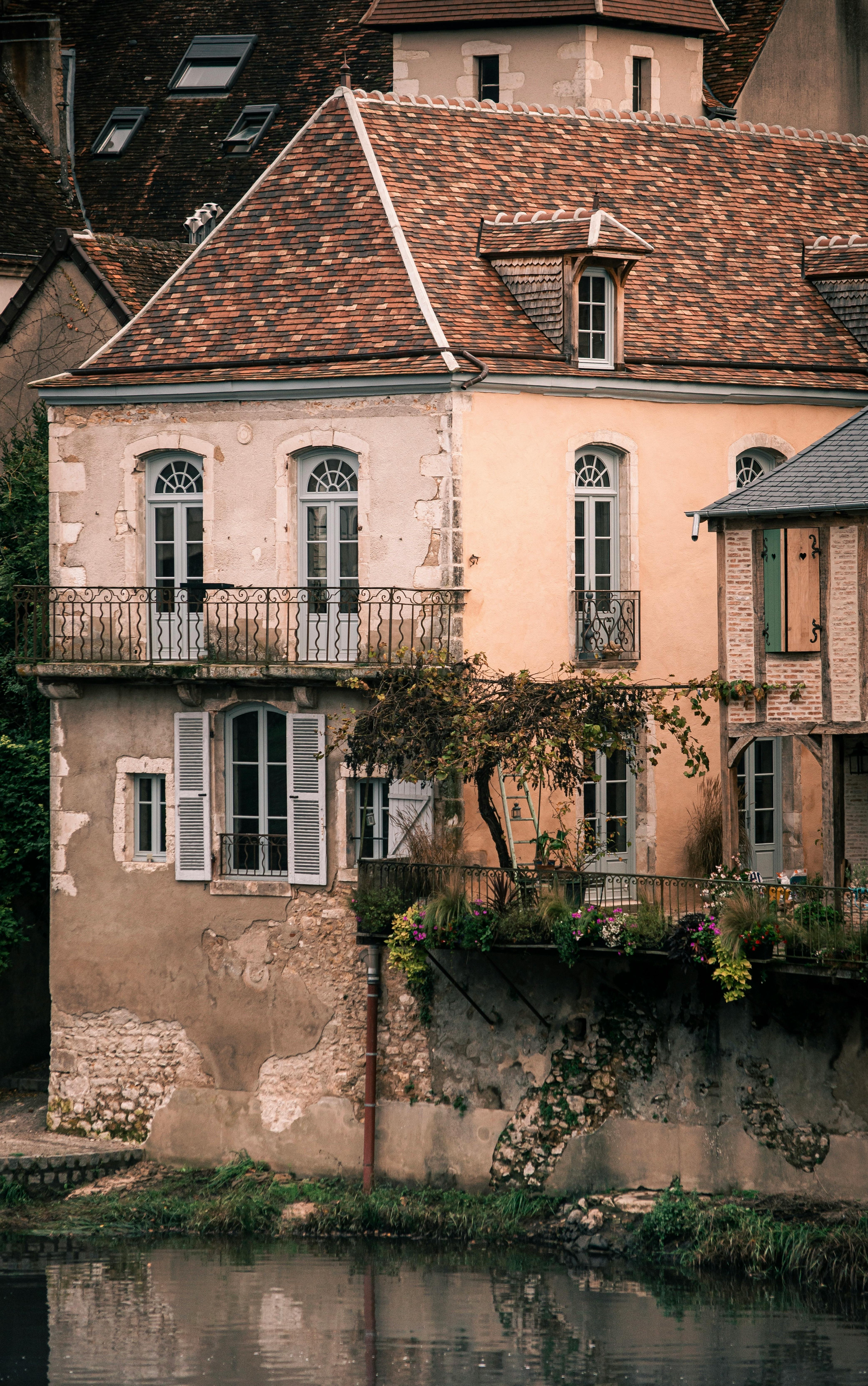 Quaint French house with rustic charm by a tranquil riverside in autumn.