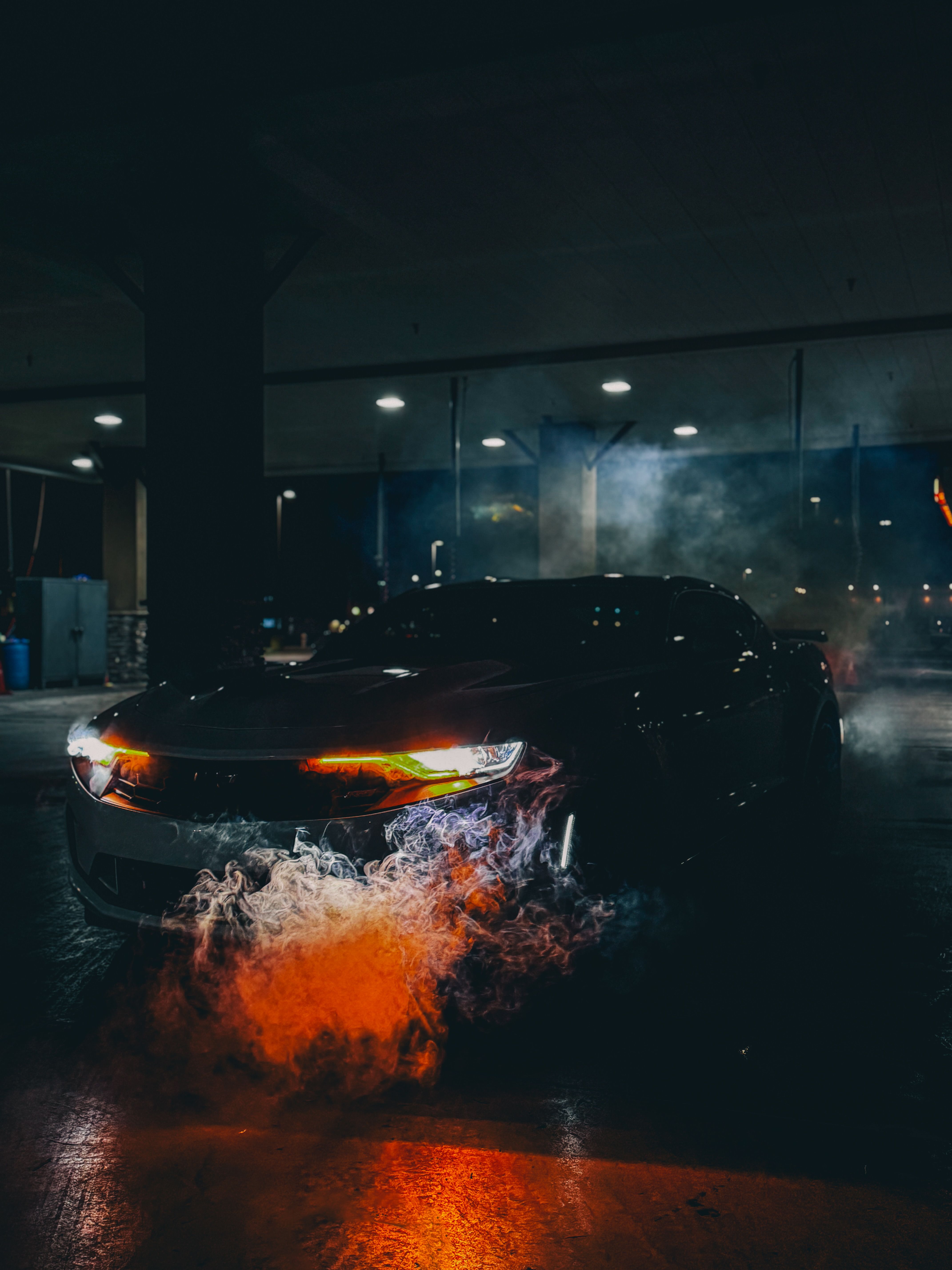 sleek-sports-car-emitting-smoke-at-night-free-stock-photo